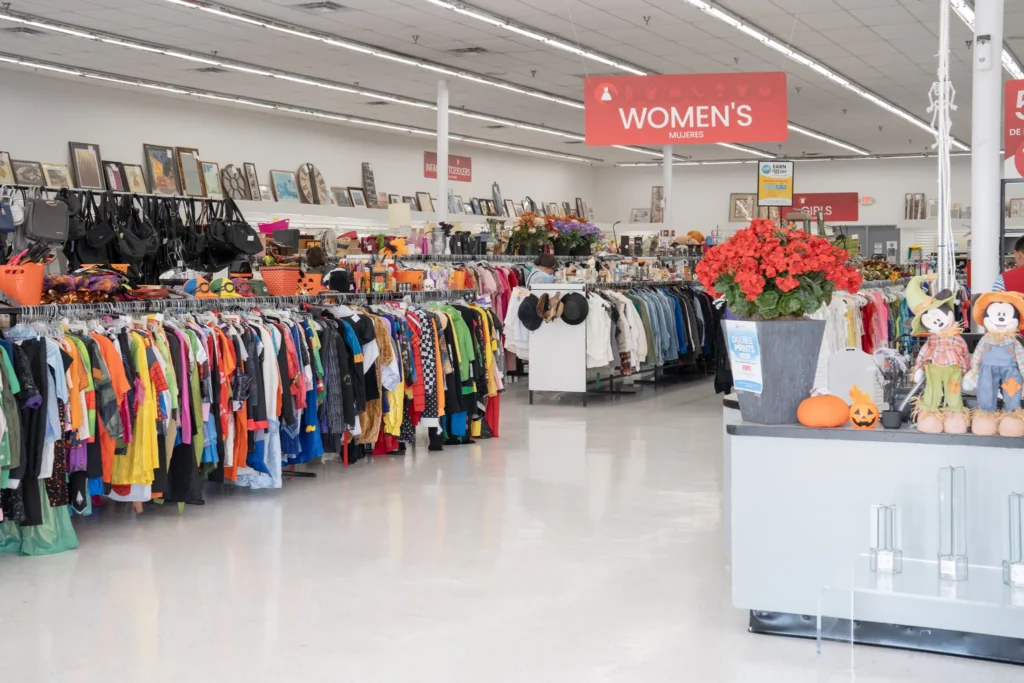 Wide interior view of clothing racks, accessories, framed art, flowers, and seasonal decorations inside Value World in Houston.