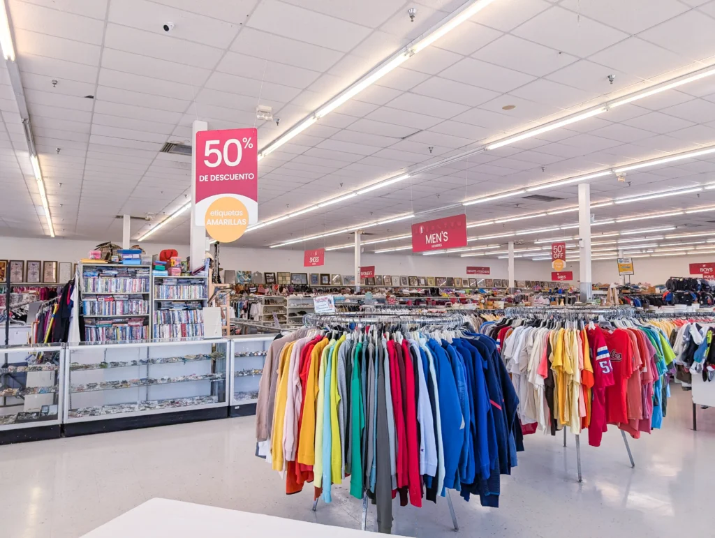 Wide interior view of colorful clothing racks and yellow-tag 50 percent off signs inside Value World Bissonnet.