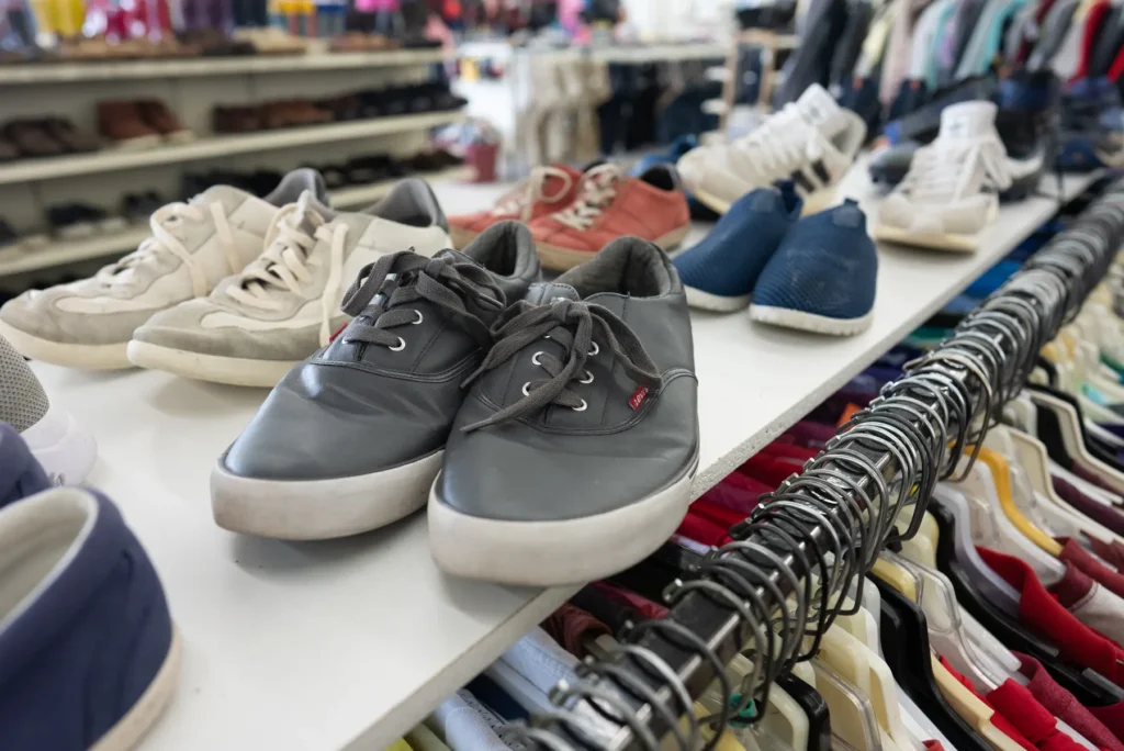 Assorted casual sneakers and shoes displayed above clothing racks at the Value World Harrisburg thrift store.