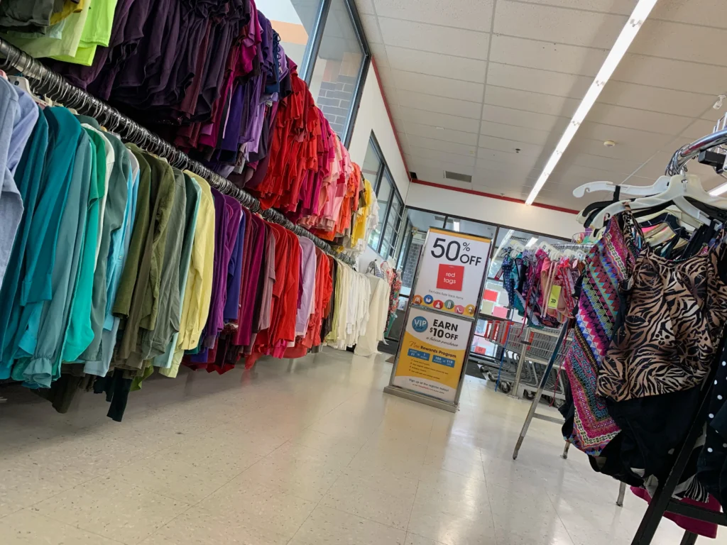 Colorful clothing and swimwear racks beside a red-tag sale sign inside the Value World Lakewood location.