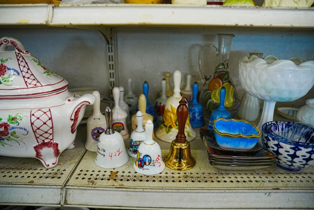 Decorative ceramic bells, serving bowls, dishes, and pottery displayed on shelves inside Value World.