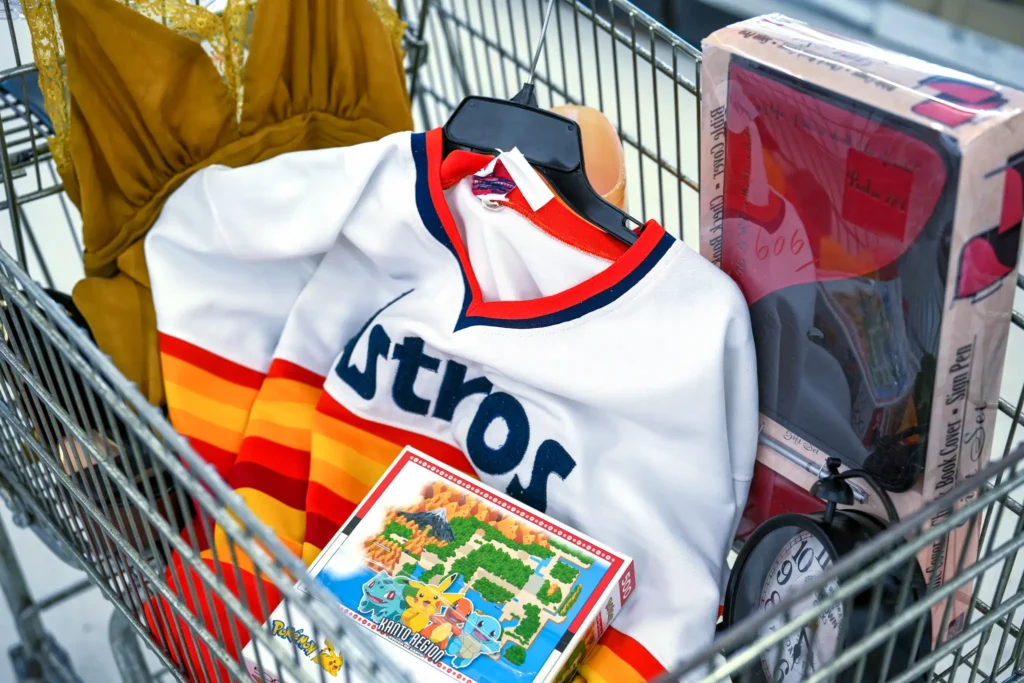 Shopping cart filled with a Houston Astros jersey, Pokémon game, boxed pen set, and other finds inside Value World Bissonnet.