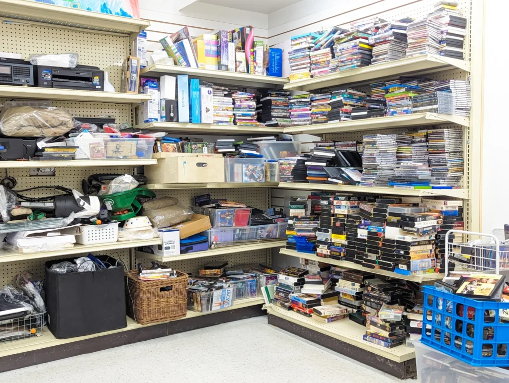 Shelves filled with DVDs, CDs, VHS tapes, and small electronics inside Value World.
