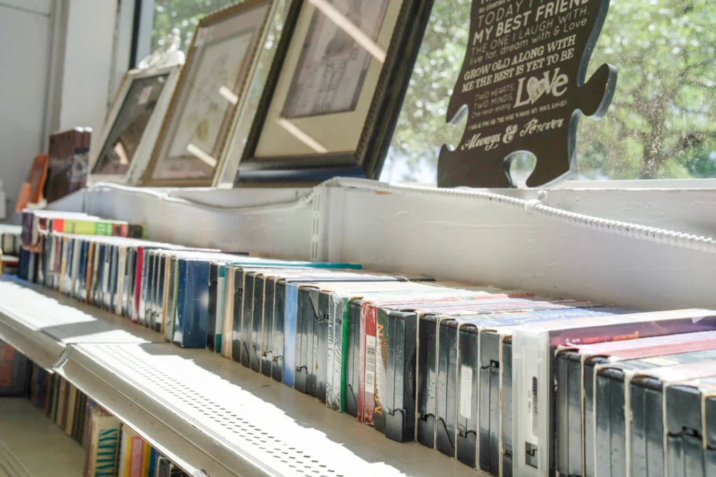 Rows of DVDs displayed on a shelf with framed artwork and decorative signs inside Value World.