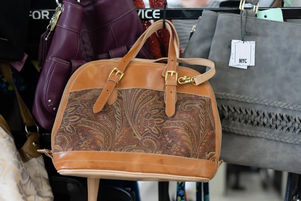 Assorted patterned, purple, and gray handbags displayed at the Value World Lakewood thrift store in Ohio.