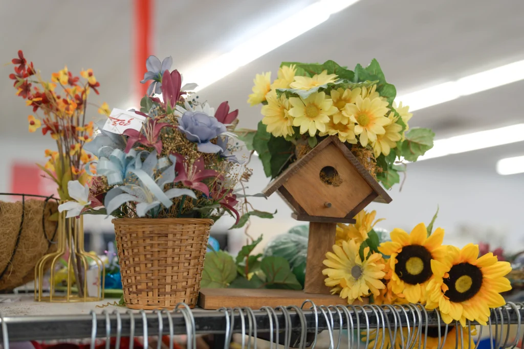 Decorative birdhouse surrounded by artificial sunflowers and floral arrangements at the Value World Harrisburg location.