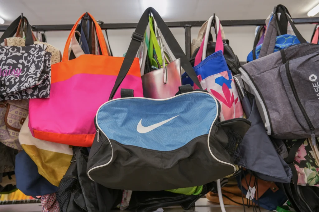 A colorful selection of tote bags, backpacks, and duffel bags hanging inside Value World.