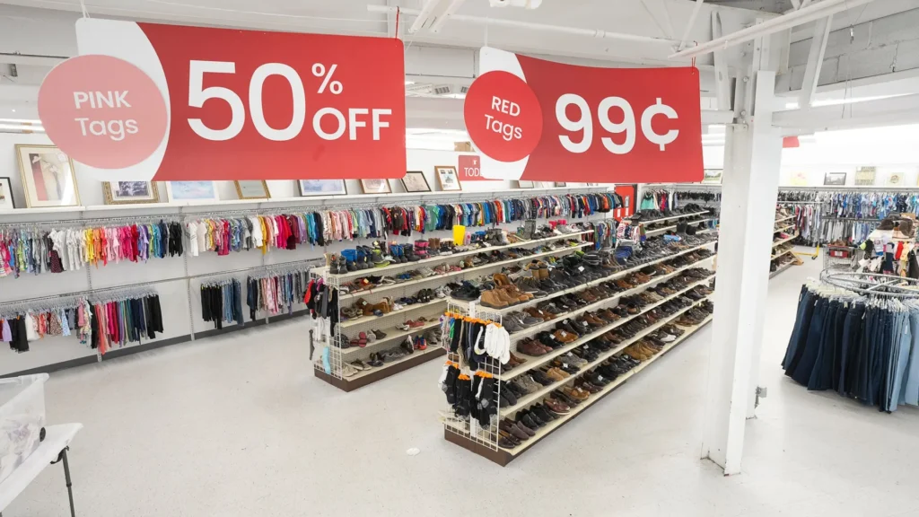 Clothing and shoe aisles beneath color-tag sale signs at Value World in North Olmsted, Ohio