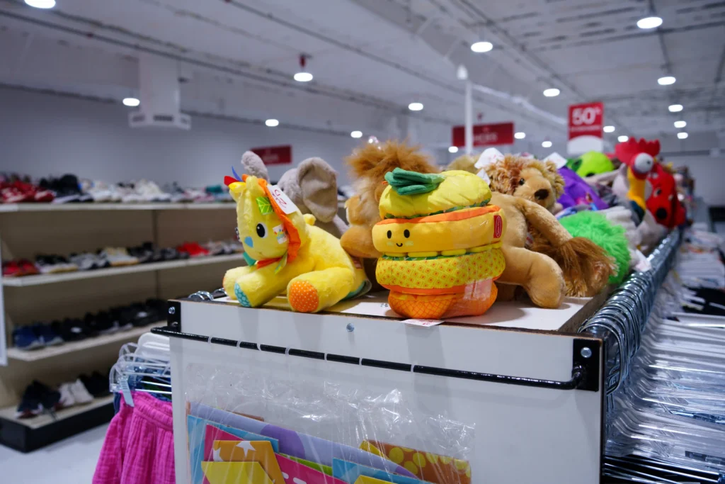 Colorful plush toys and stuffed animals displayed above clothing racks inside the Value World Barker Cypress store.